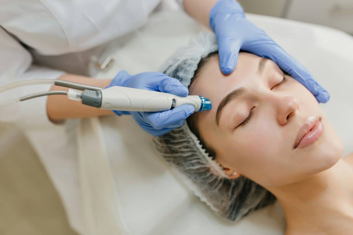 Dermatologist applying glycolic acid peel therapy to patient's cheek during in-office treatment